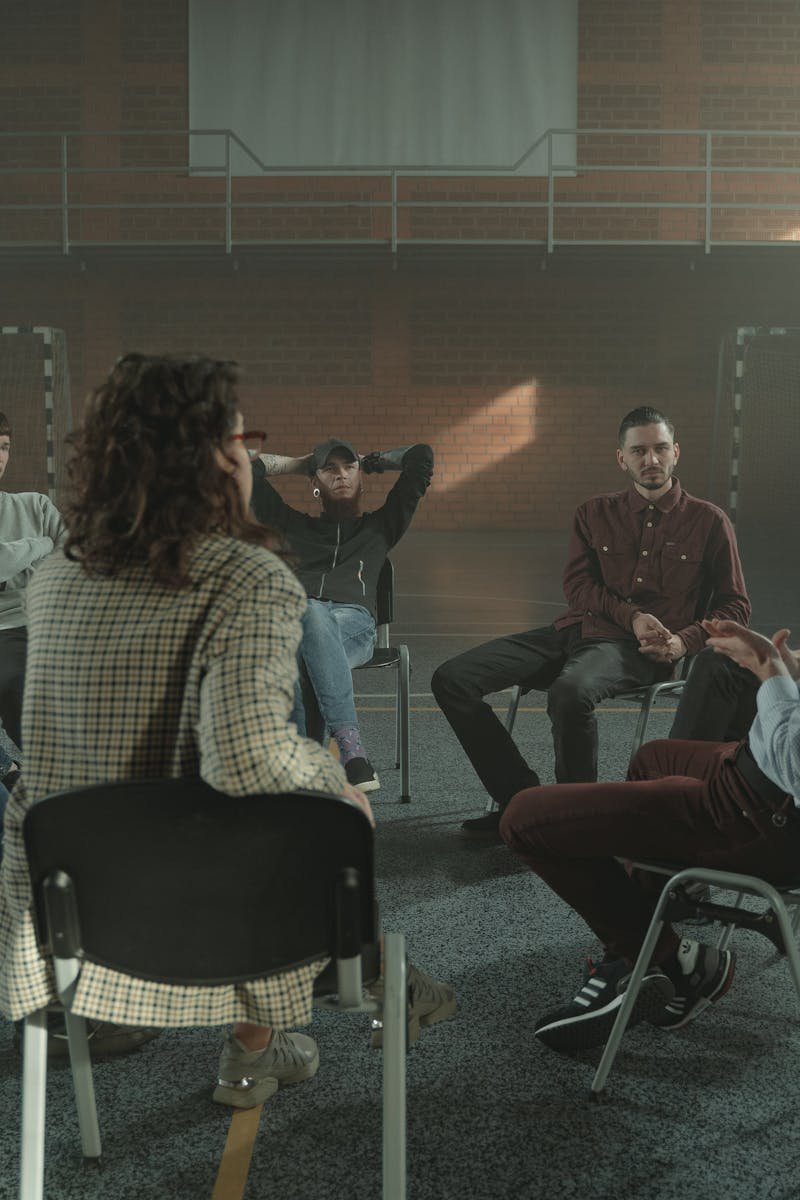 A diverse group engages in a therapy session inside a gym, fostering mental health support.